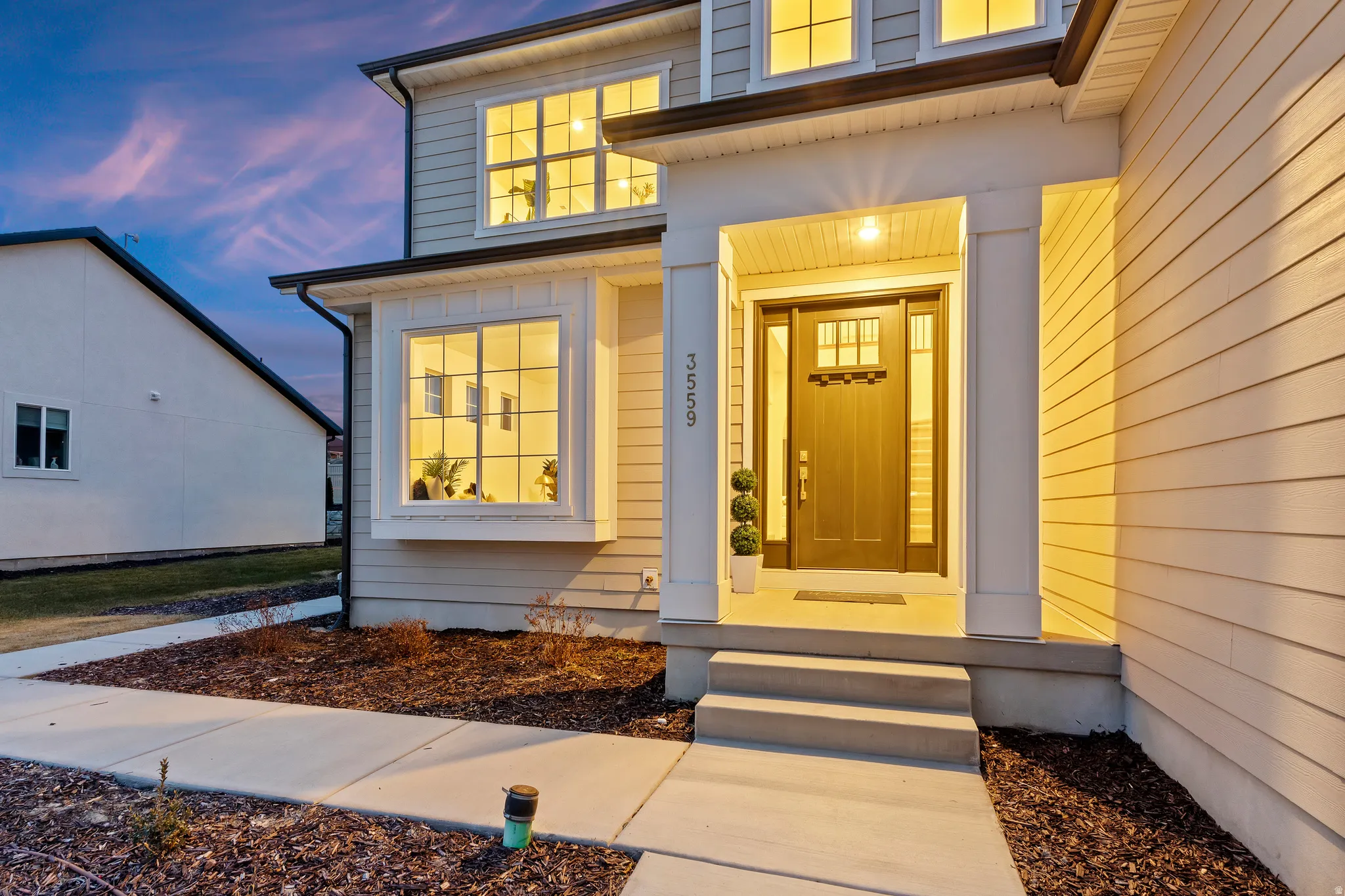 Two-story exterior with horizontal siding, covered entry porch, bay window, and transom-paneled front door