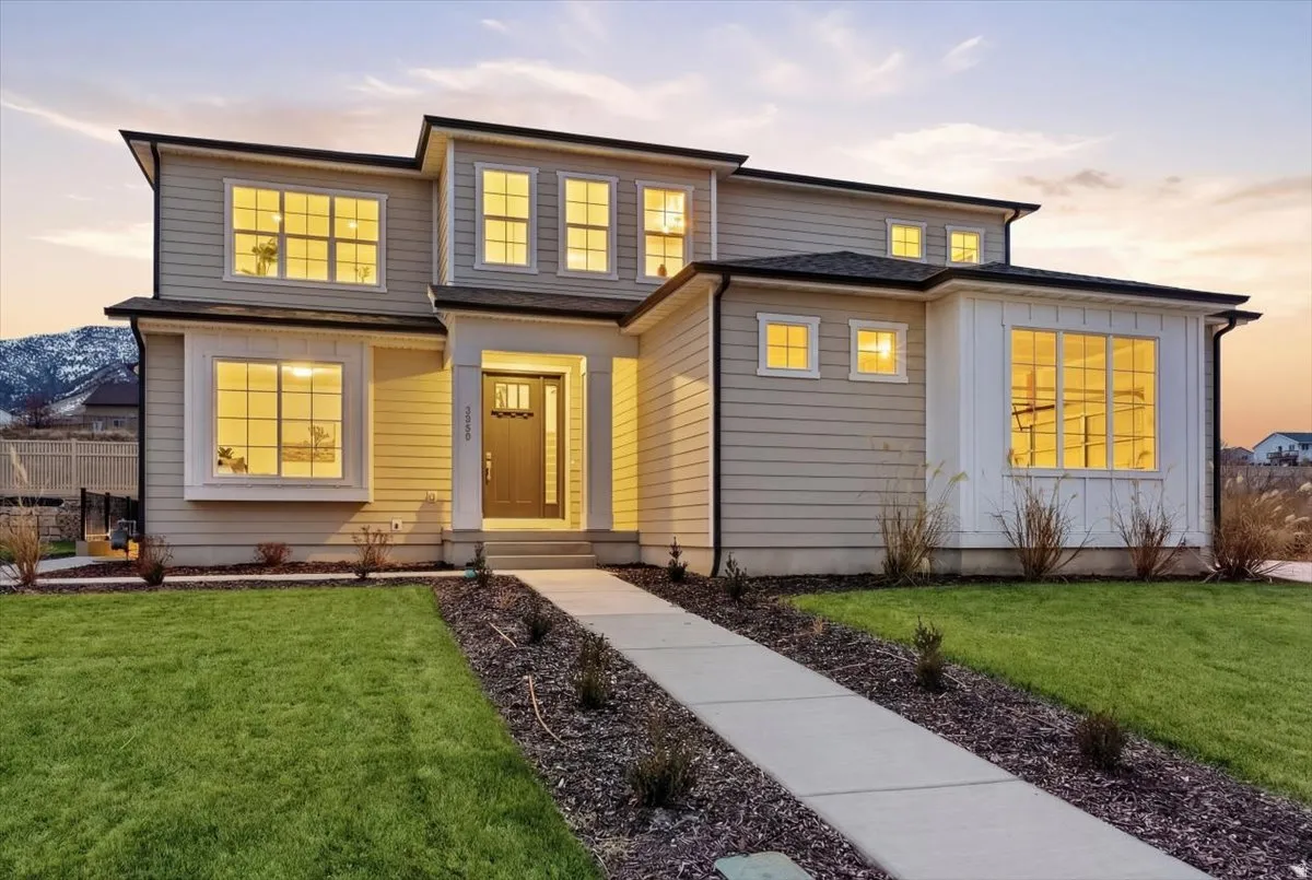 Contemporary multi-story residence with a concrete walkway, established landscaping, and siding exterior