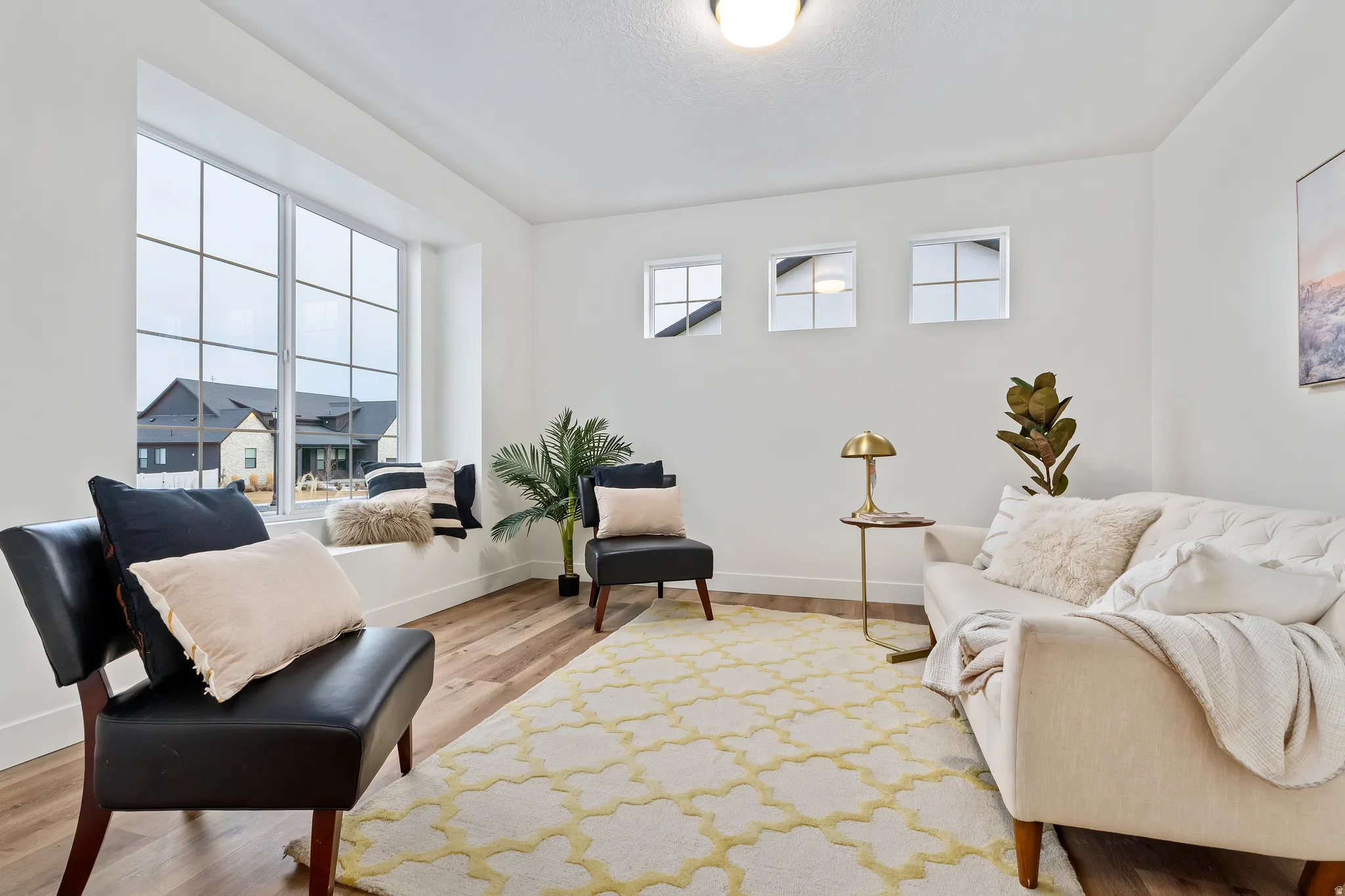 Wood-finish flooring, white walls, large bay window with window bench, three transom windows, and a flush mount ceiling light