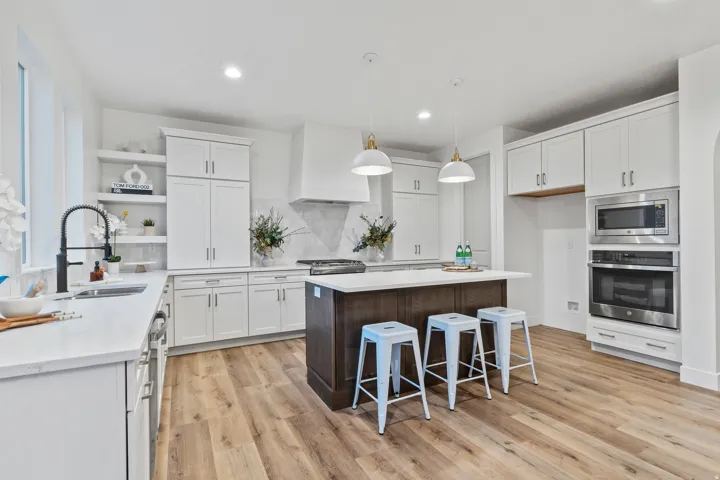 Kitchen featuring wood-finish flooring, white cabinetry, a dark wood-finish island, stainless steel appliances, and recessed lighting