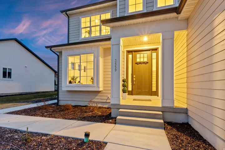 Two-story exterior with horizontal siding, covered entry porch, bay window, and transom-paneled front door