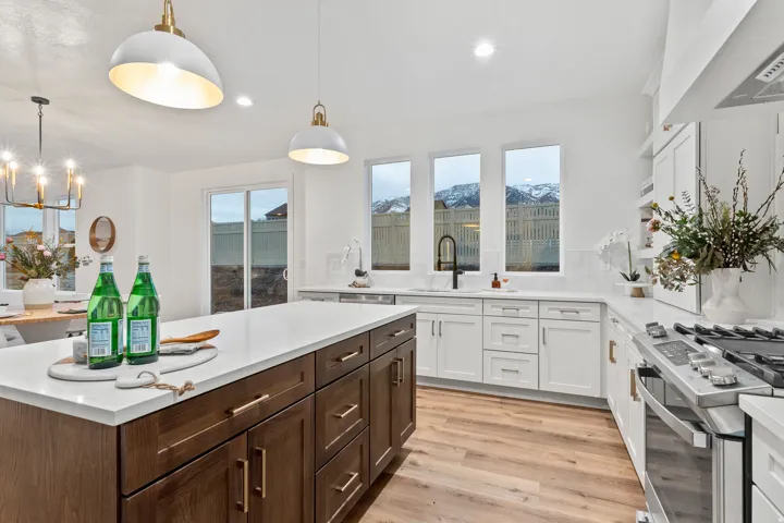 Spacious kitchen featuring a large central island with wood cabinetry, white countertops, stainless steel appliances, and wood-finish flooring