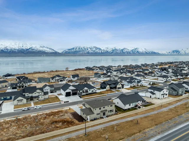Residential development featuring a variety of housing styles, paved roadways, and a prominent water body with a mountainous backdrop