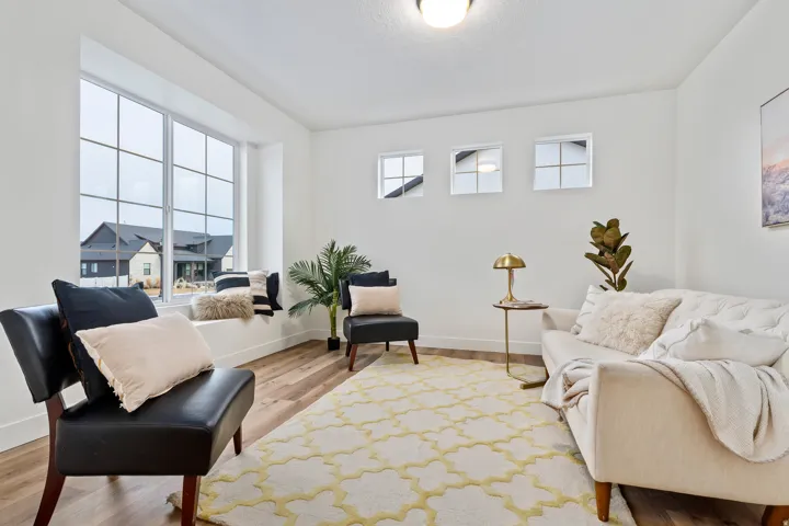 Wood-finish flooring, white walls, large bay window with window bench, three transom windows, and a flush mount ceiling light