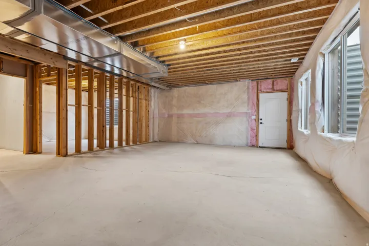 Unfinished basement with exposed ceiling joists, concrete flooring, framed wall sections, and multiple windows providing natural illumination