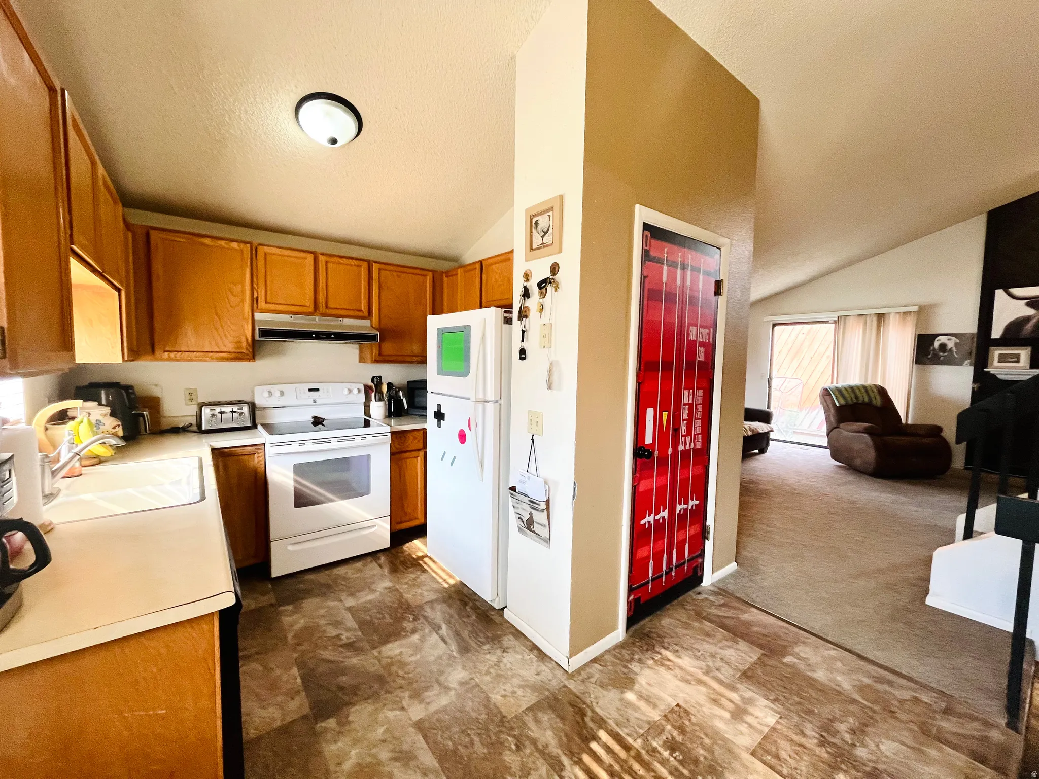Bright, functional kitchen with plenty of space for everyday living, wood cabinetry, and white appliances.