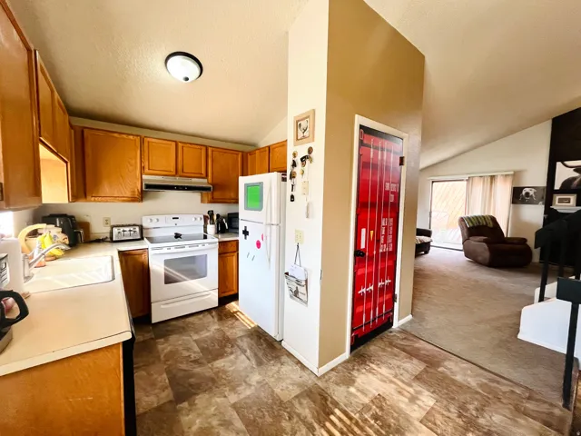 Bright, functional kitchen with plenty of space for everyday living, wood cabinetry, and white appliances.