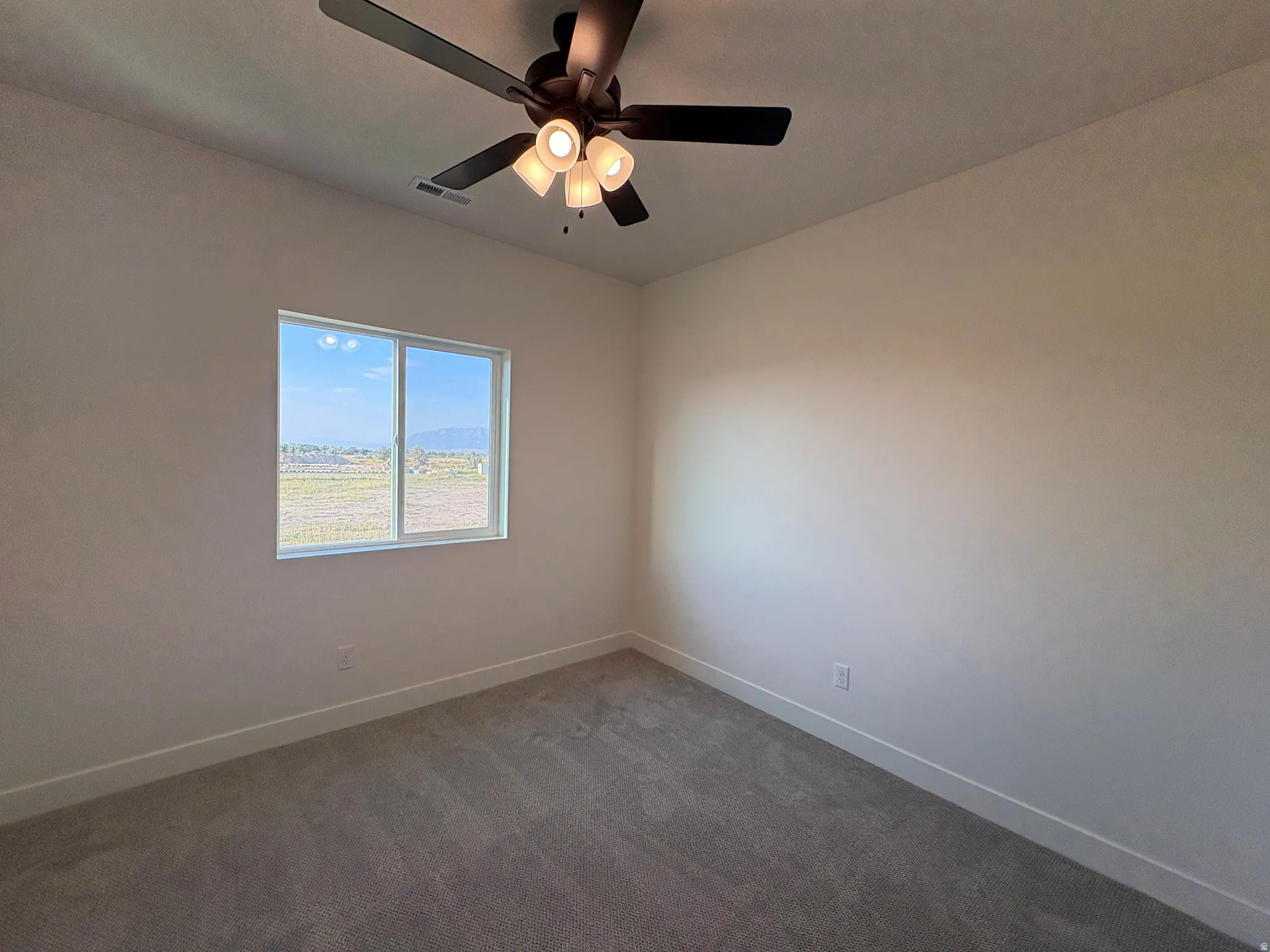 White walls, grey carpet flooring, and a ceiling fan with integrated lighting