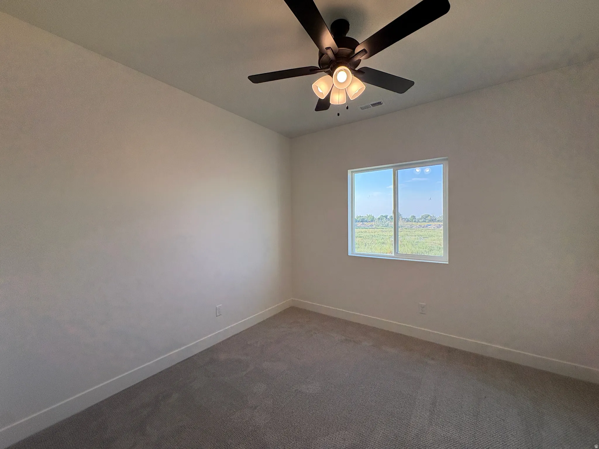 Expansive wall space, multi-pane window, flush-mount ceiling fan with integrated lighting, neutral-toned carpeting