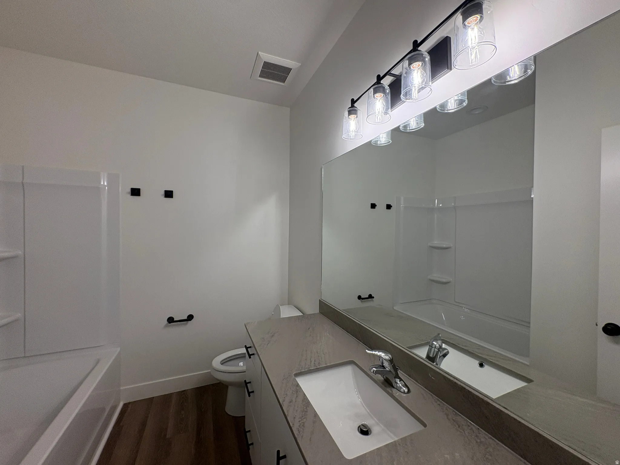 White vanity with a single sink, light grey countertop, and a large wall mirror