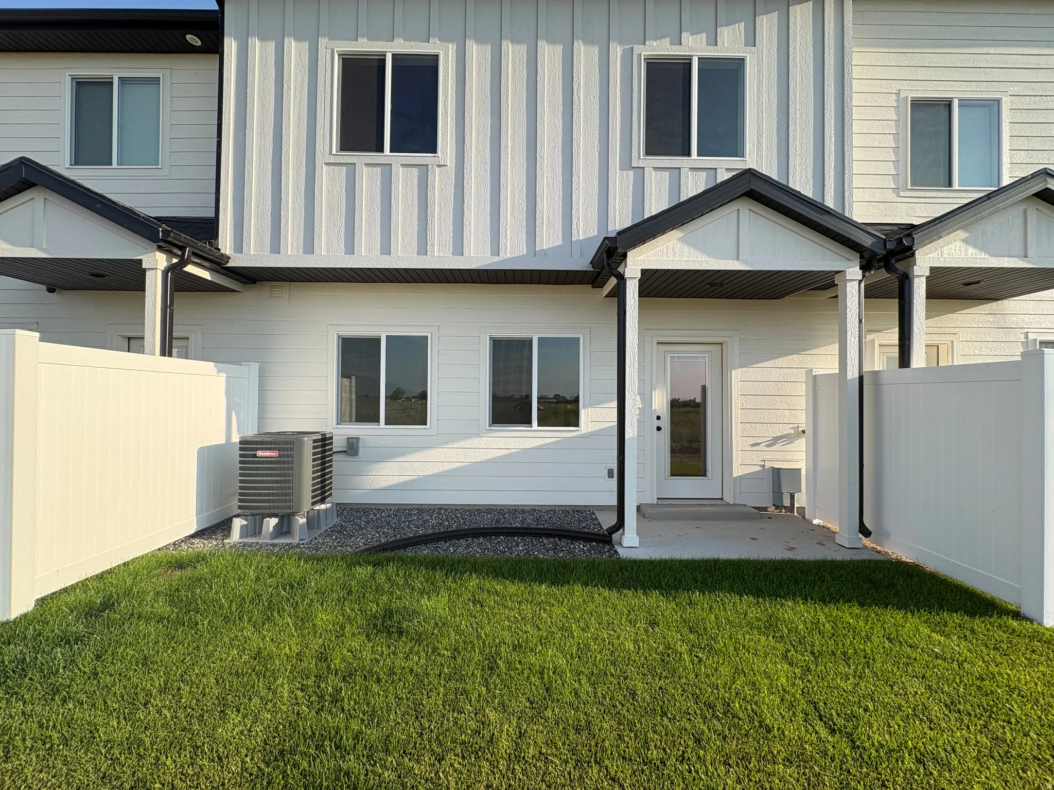 Private patio with a glass-paneled door, enclosed by a white privacy fence