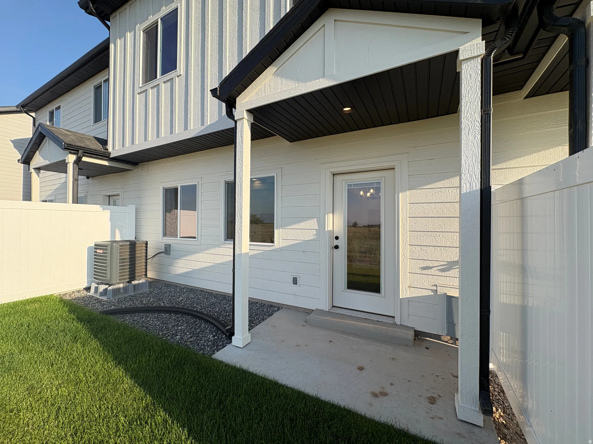 Rear patio with concrete slab, white vinyl siding, and black gutters