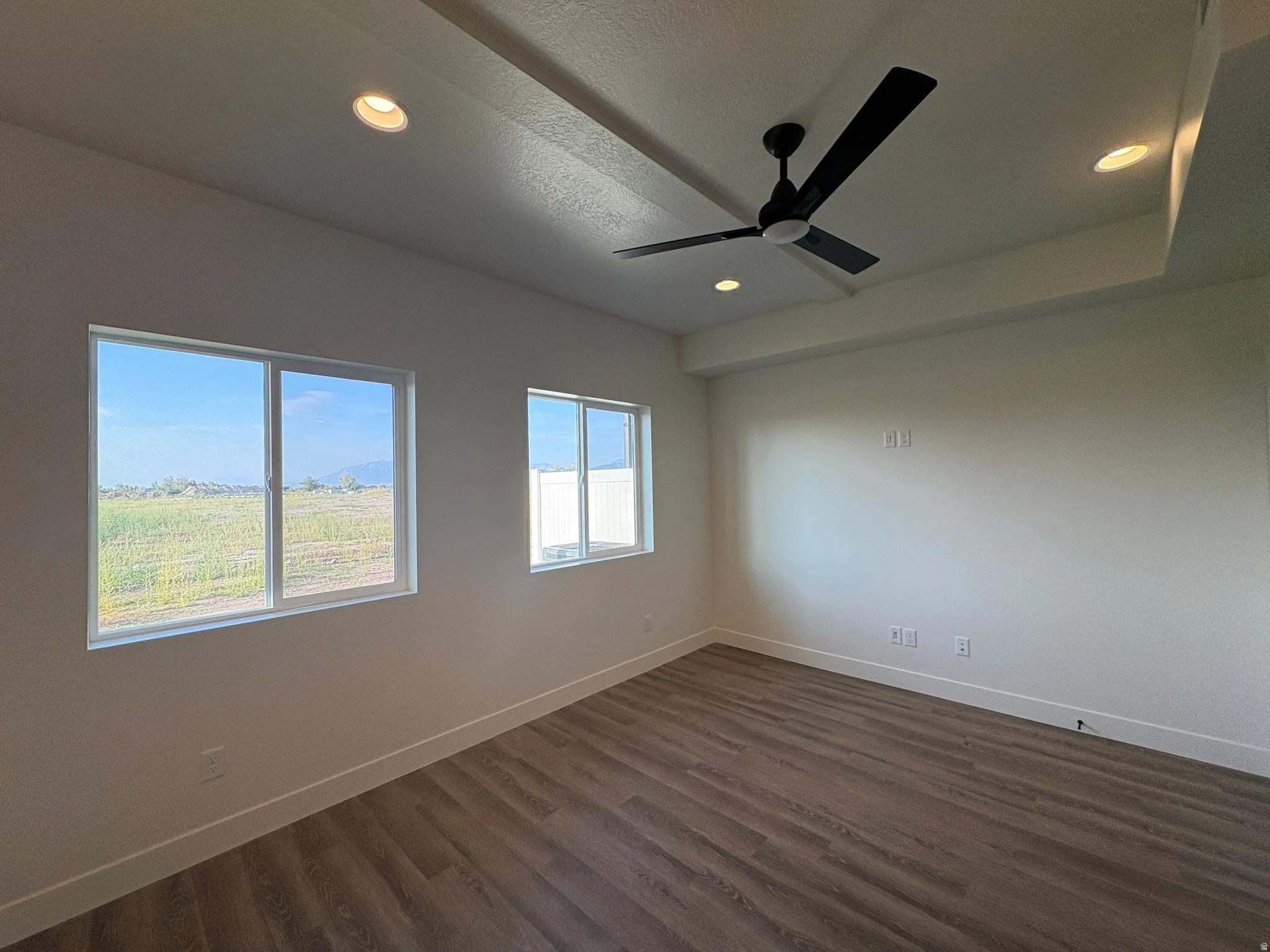Tray ceiling with recessed lighting, wood-finish flooring, and a modern ceiling fan
