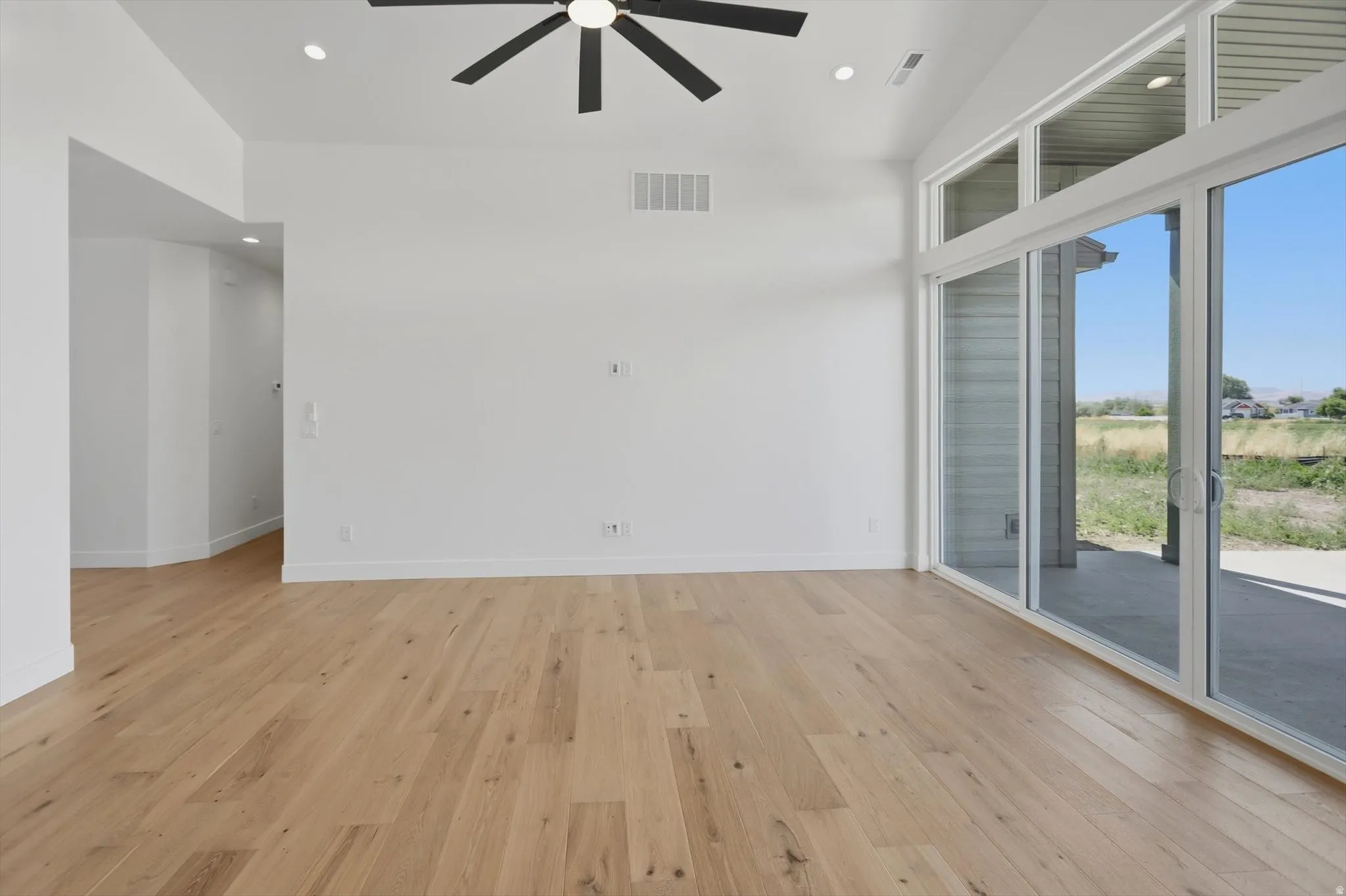 Vaulted ceilings with recessed lighting, wood-finish flooring, and a contemporary ceiling fan