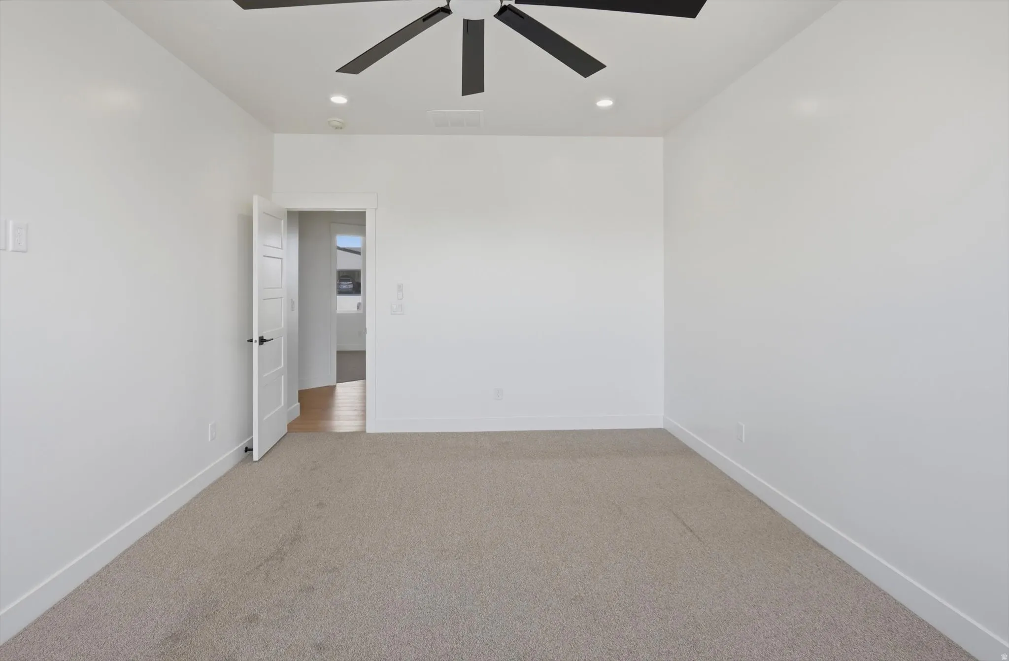Neutral wall color, recessed lighting, and a ceiling fan with black blades