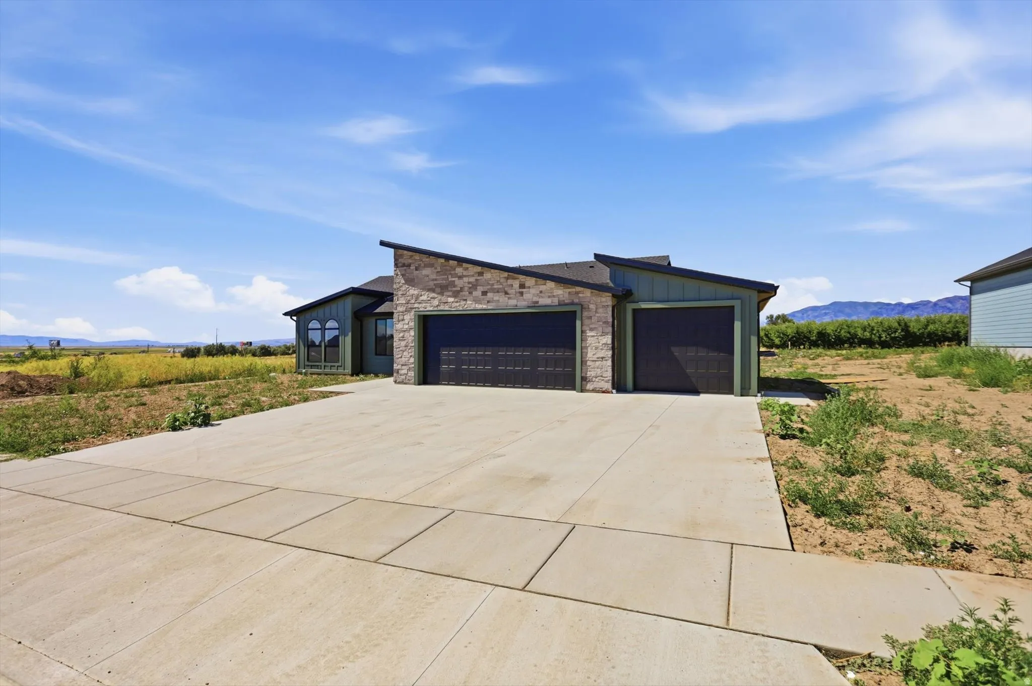 Contemporary single-story residence with a stone and siding exterior, featuring an attached two-car garage