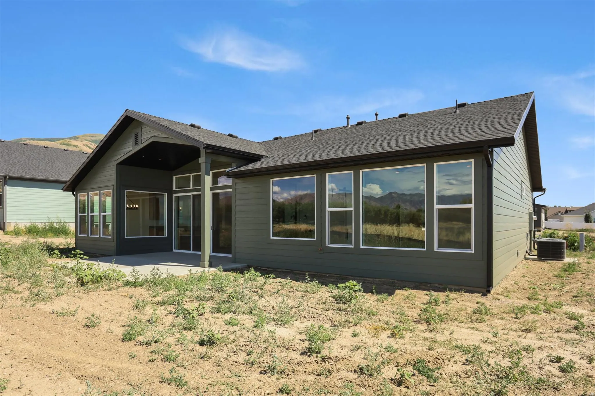 Exterior featuring large windows, a covered patio, and siding