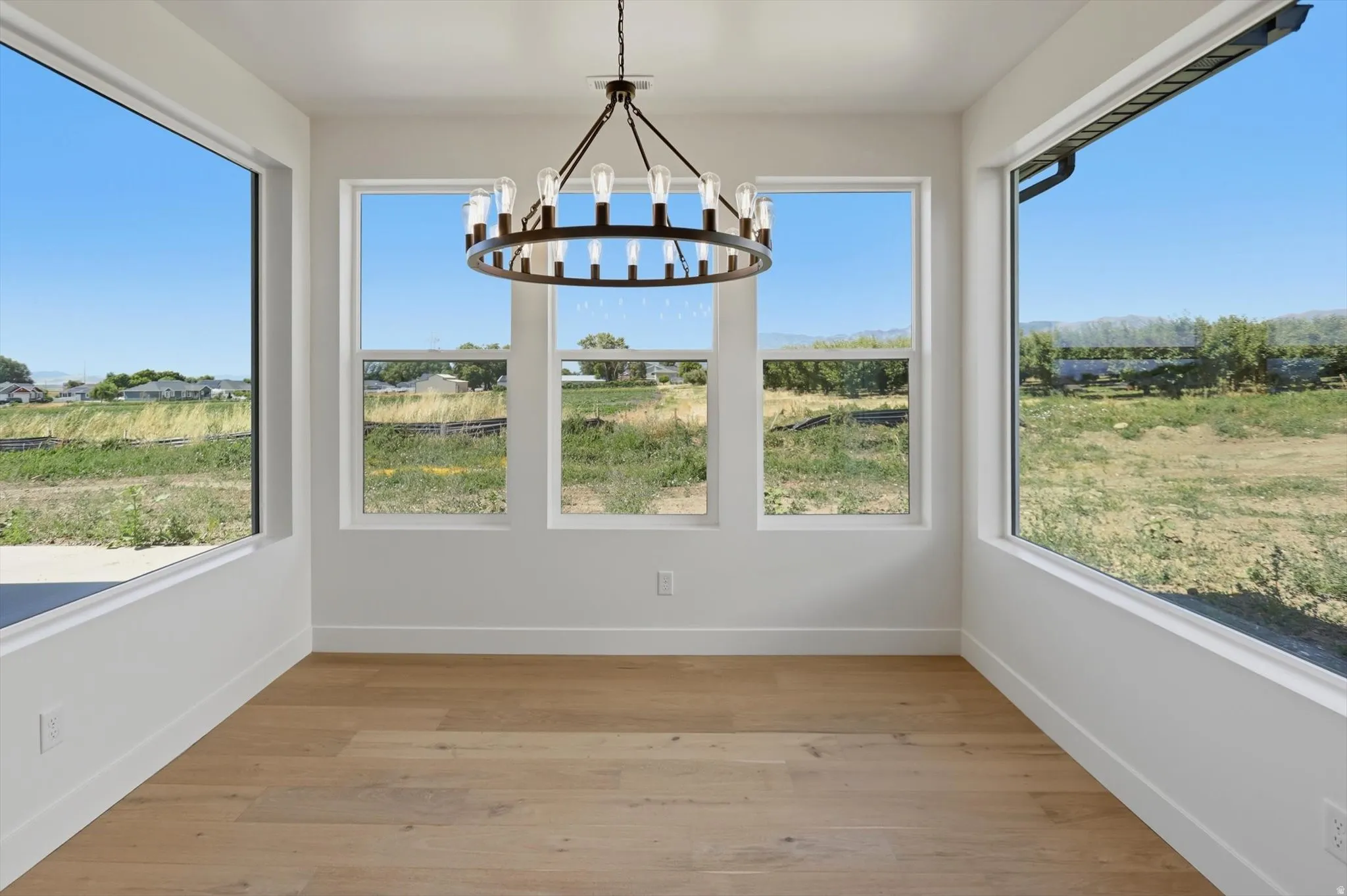 Expansive windows, wood-finish flooring, and a modern chandelier