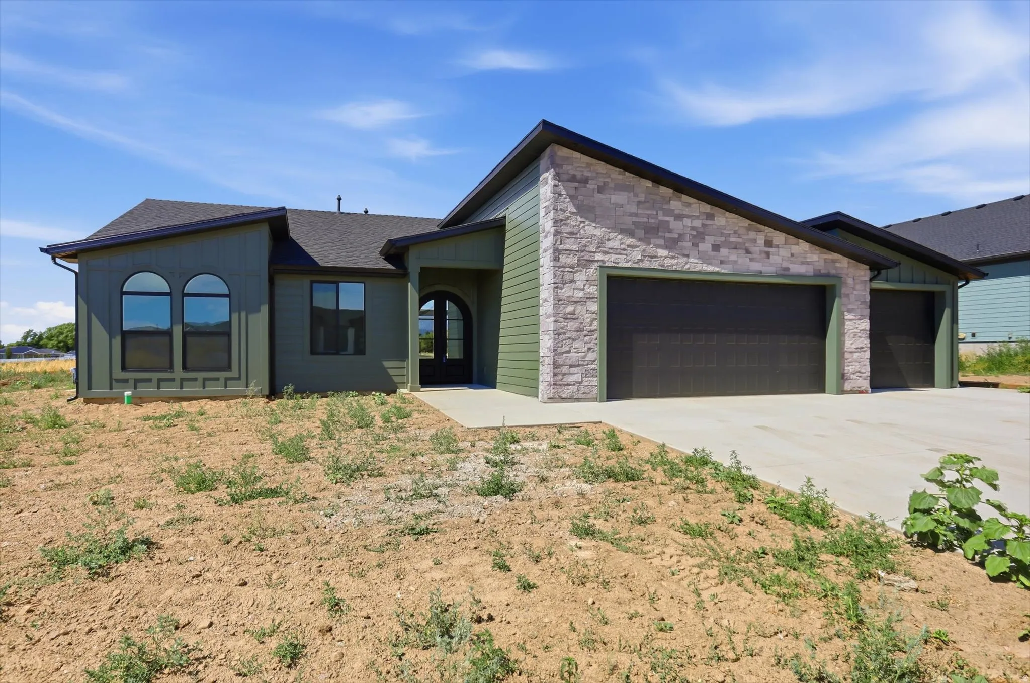 Single-story exterior with a covered entry, dark asphalt shingle roof, and a two-car garage