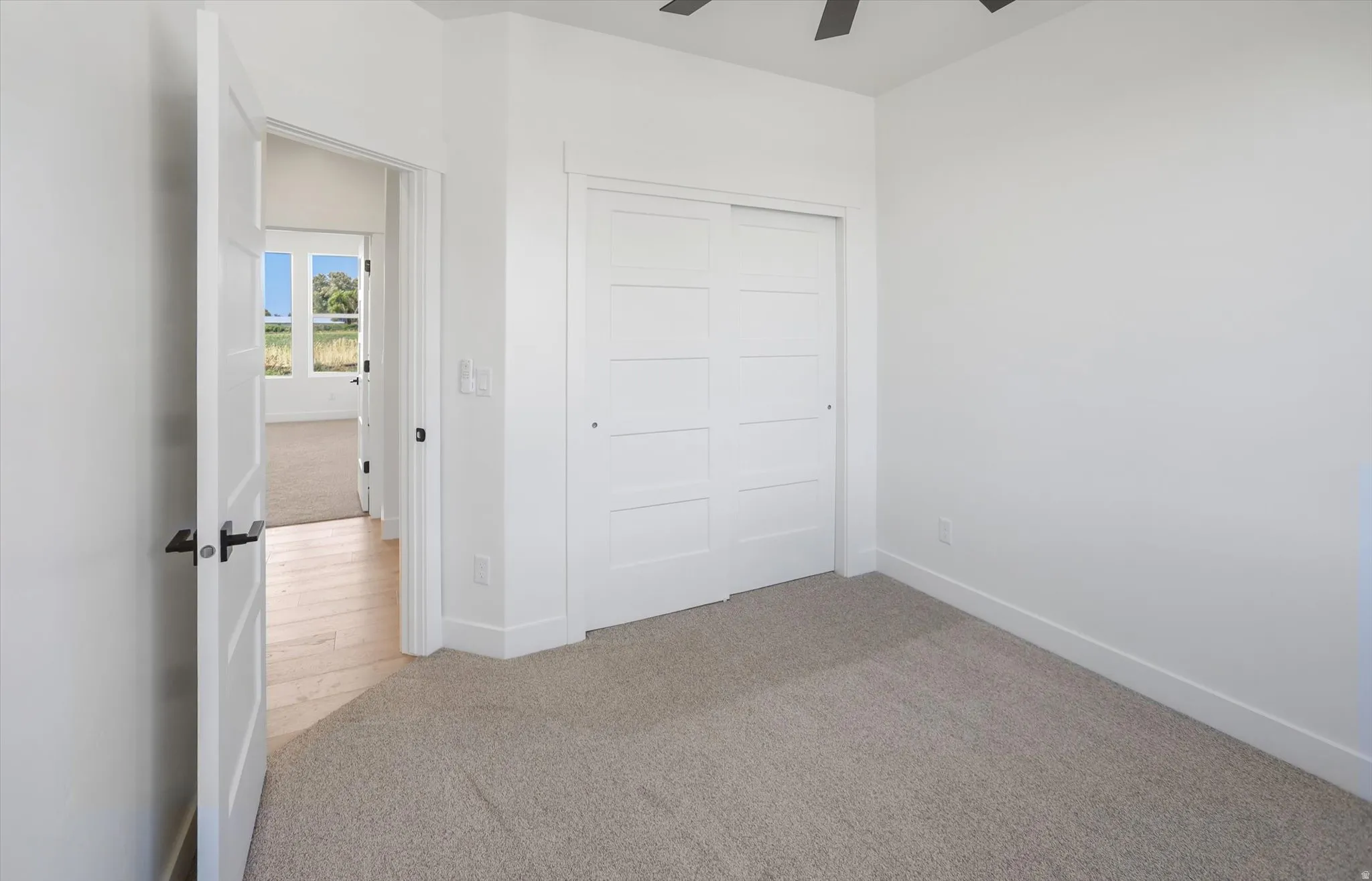 Neutral tone carpet flooring and white walls with a built-in closet featuring white paneled sliding doors