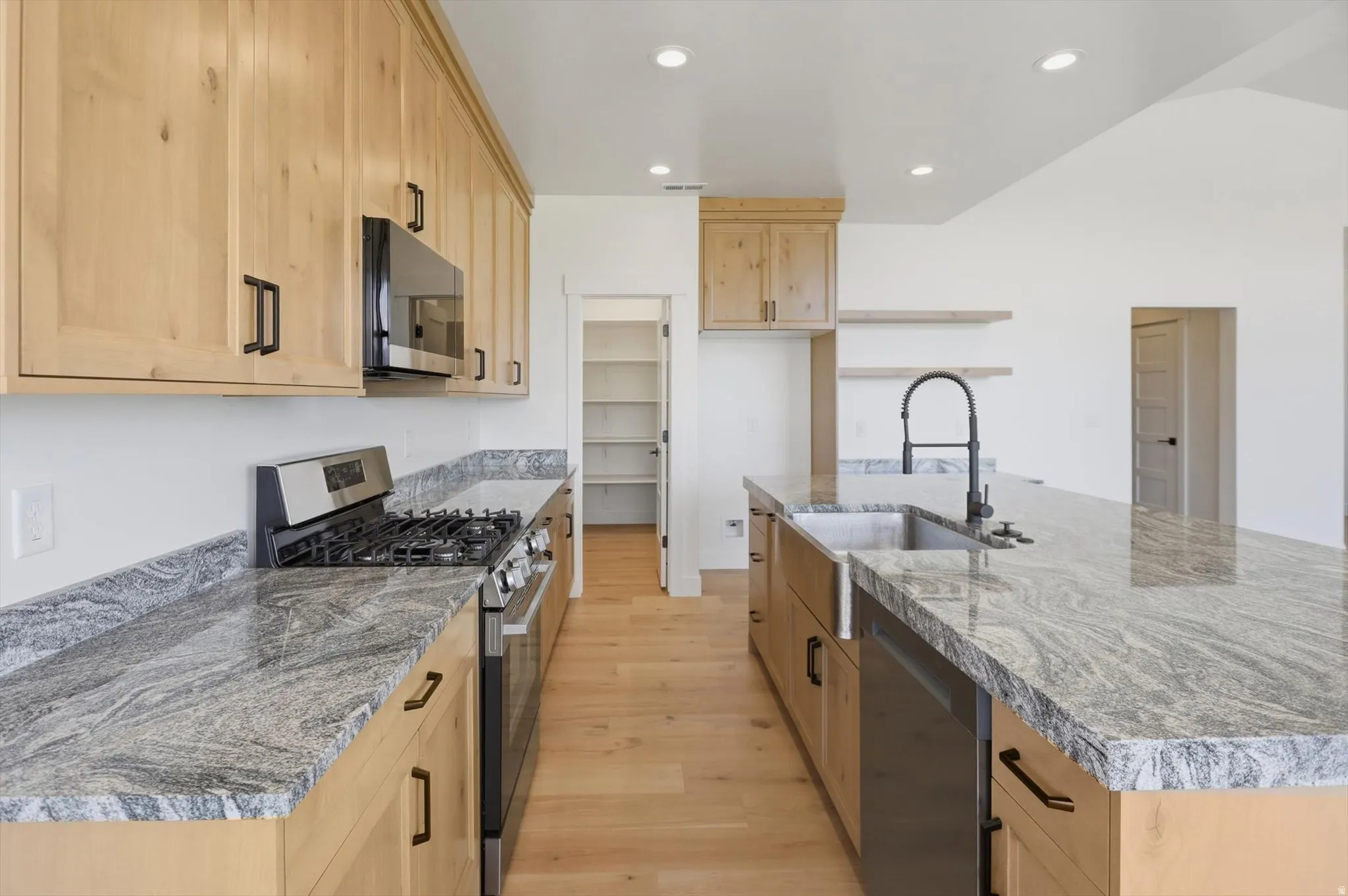 Kitchen featuring light wood-finish cabinetry, stainless steel appliances, and stone countertops