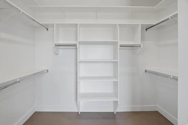 Built-in closet system featuring white shelving, multiple hanging rods, and a central storage unit