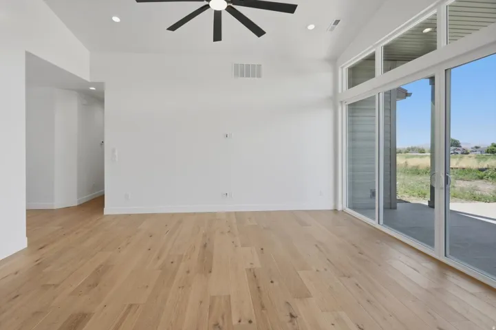 Vaulted ceilings with recessed lighting, wood-finish flooring, and a contemporary ceiling fan