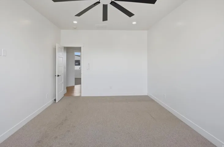 Neutral wall color, recessed lighting, and a ceiling fan with black blades