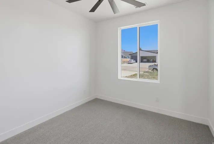 White walls with a light gray carpet and a modern ceiling fan