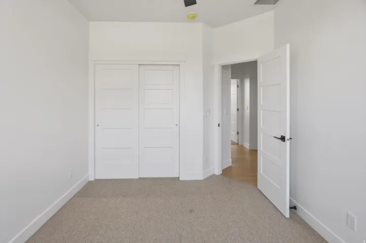 Light-colored carpeting, white walls, and a white interior door with matte black hardware