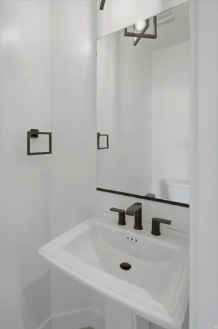 Pedestal sink with dark bronze faucet, framed mirror, and coordinating dark bronze towel ring