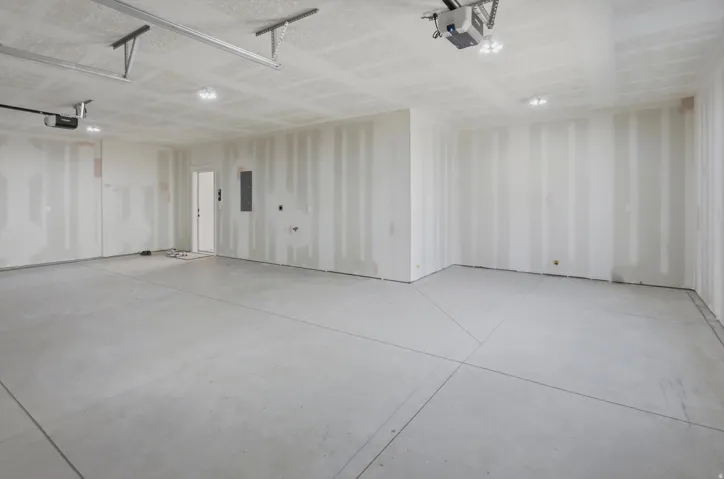 Expansive garage with concrete flooring, recessed lighting, and a white interior door