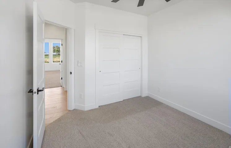 Neutral tone carpet flooring and white walls with a built-in closet featuring white paneled sliding doors