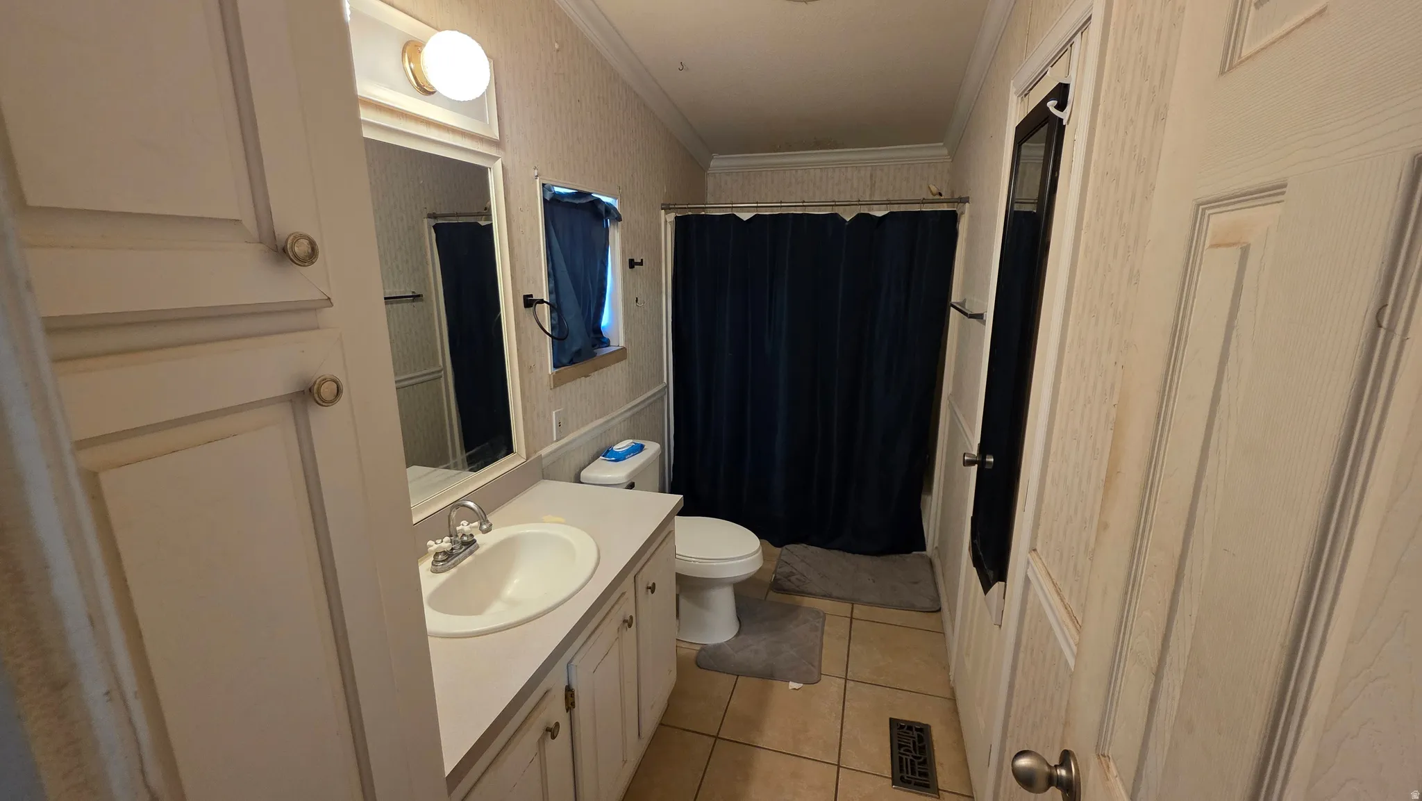 Vanity with integrated sink, tile flooring, built-in storage cabinet, and a framed wall mirror