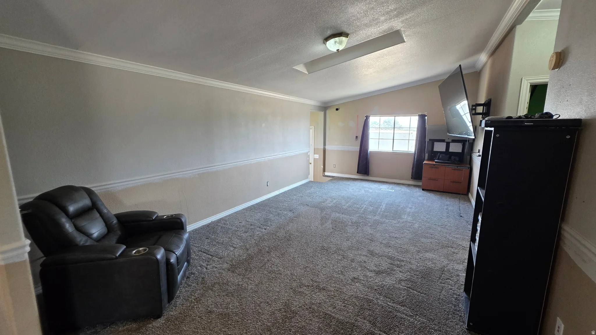 Vaulted ceiling with an integrated light fixture, crown molding, and two-tone wall treatment