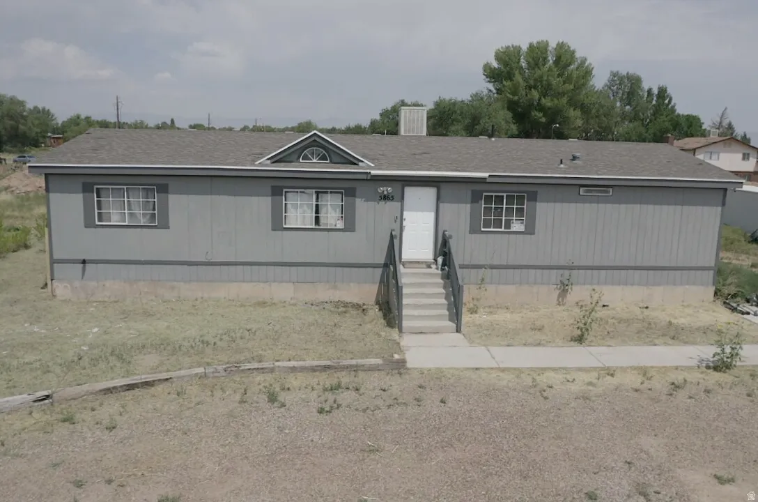 Gray exterior siding with white trim, a gabled dormer with an arched window, a gray shingle roof, and a concrete walkway