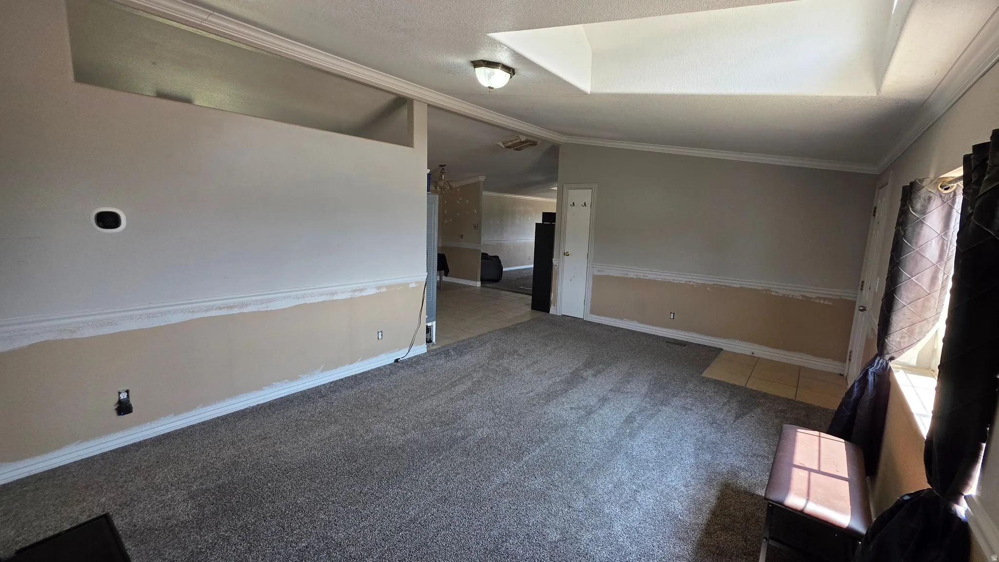 Tray ceiling feature, crown molding, gray carpet flooring, window with natural light, and a built-in shelf