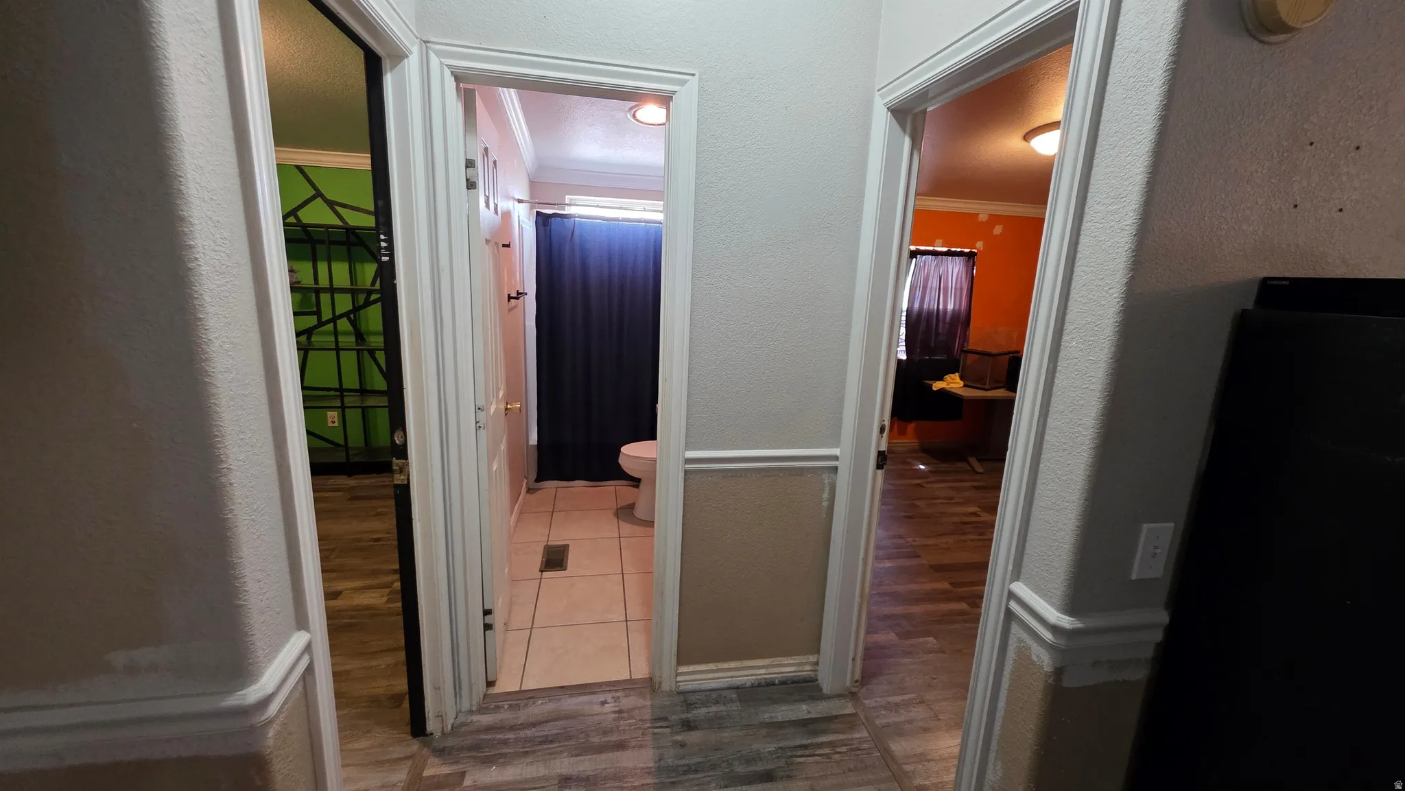 Hallway featuring wood-finish flooring, chair rail molding, and three doorways
