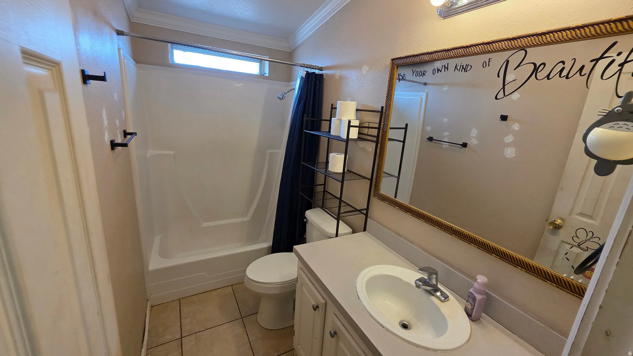 Tile flooring, built-in vanity with integrated sink, framed wall mirror, shower/tub combination, and transom window