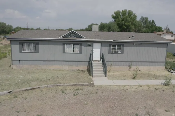 Gray exterior siding with white trim, a gabled dormer with an arched window, a gray shingle roof, and a concrete walkway