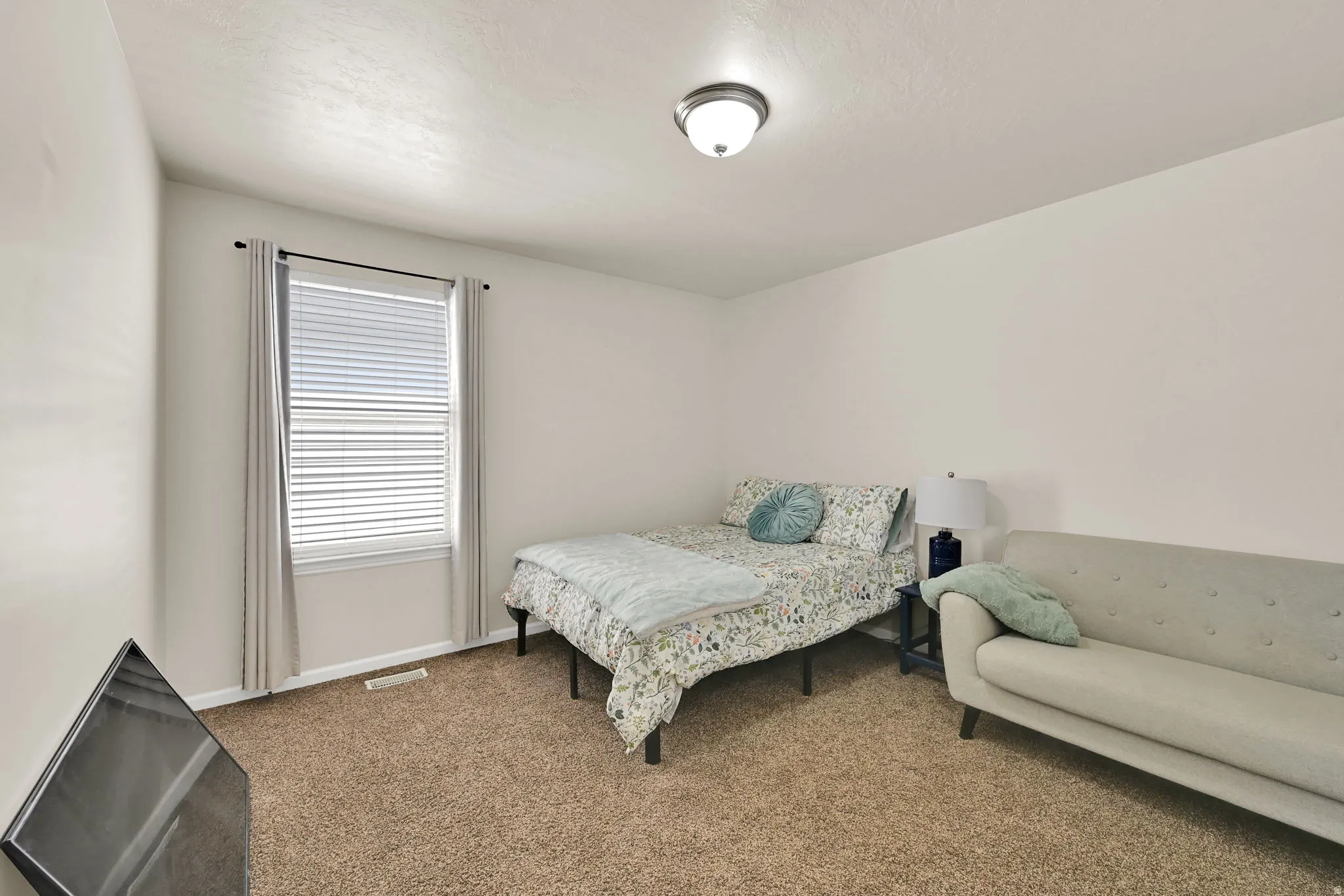 Carpeted room with a single window featuring blinds, an overhead flush-mount light fixture, and neutral wall tones