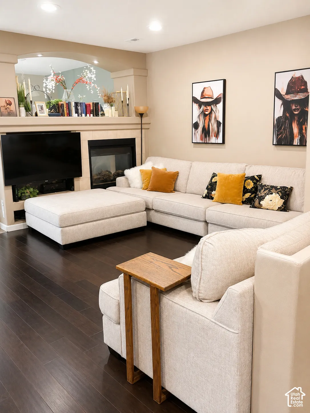 Dark wood-finish flooring, recessed lighting, built-in media niche, and a fireplace with a stone surround