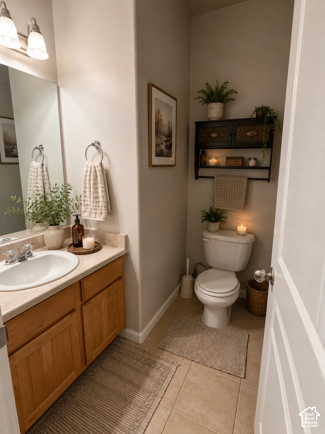 Vanity with a single basin sink and a chrome faucet set, wood-finish cabinetry, neutral-toned countertop, wall-mounted light fixture, and tile flooring