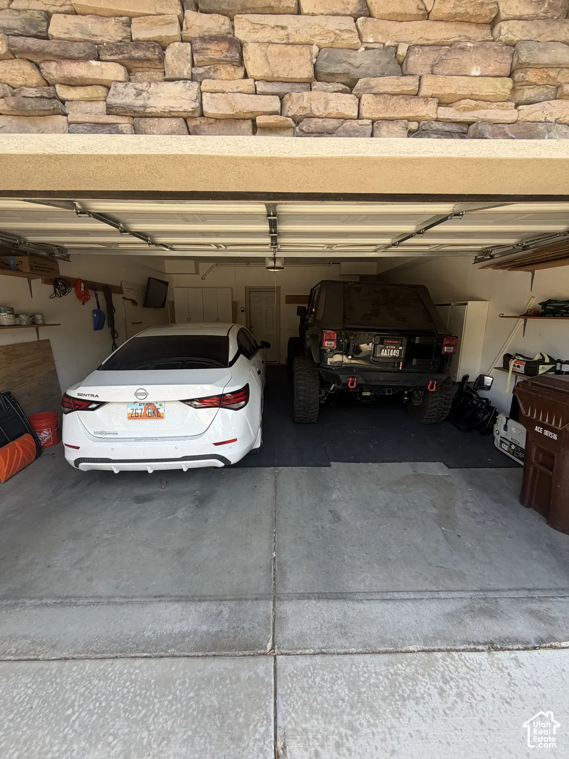 Two-car garage with overhead lighting and a stone-clad exterior