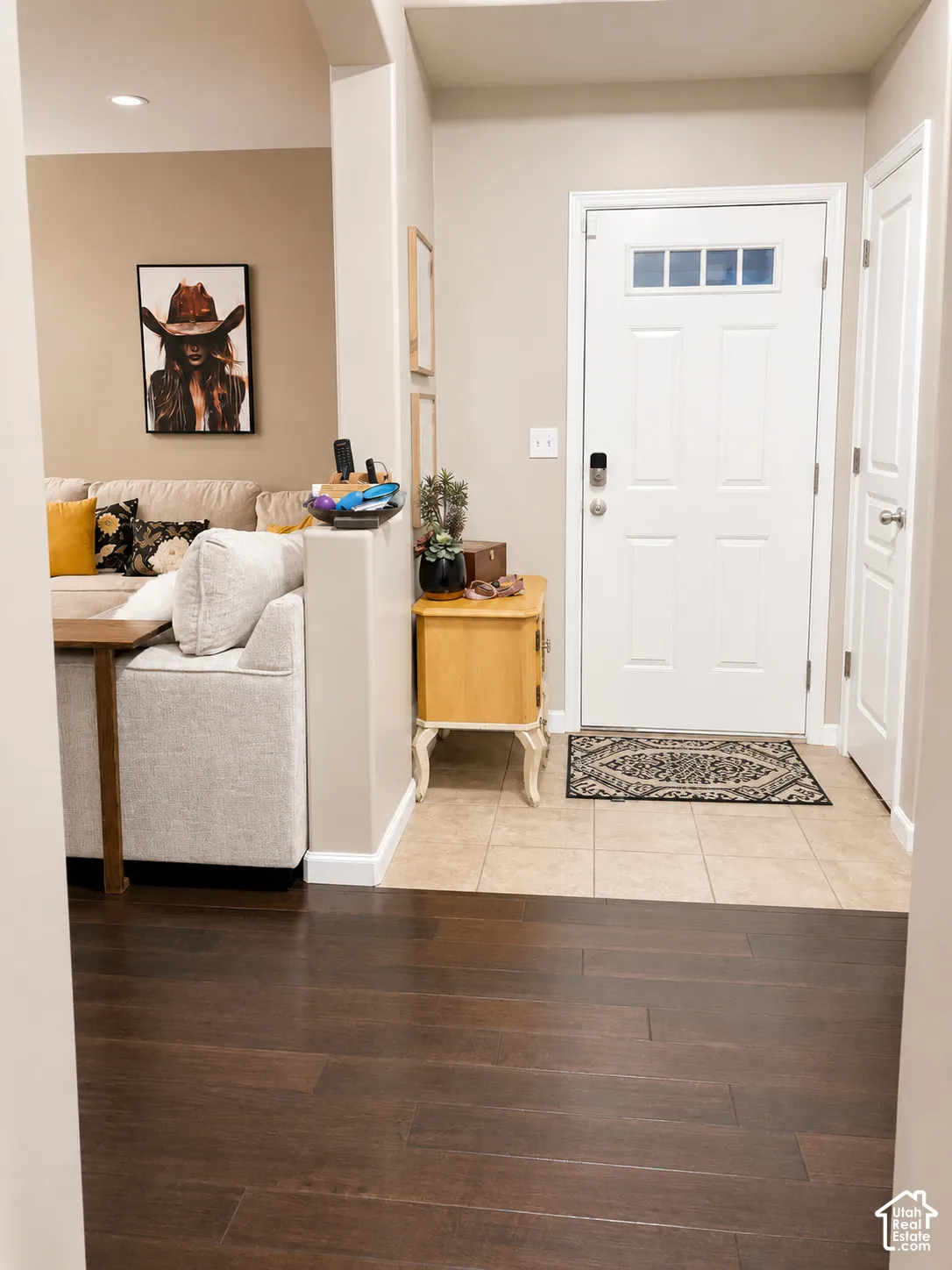 Wood-finish flooring, tiled entry, and a paneled front door with transom windows