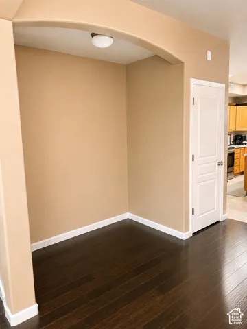 Arched entryway featuring wood-finish flooring, neutral wall tones, and overhead illumination