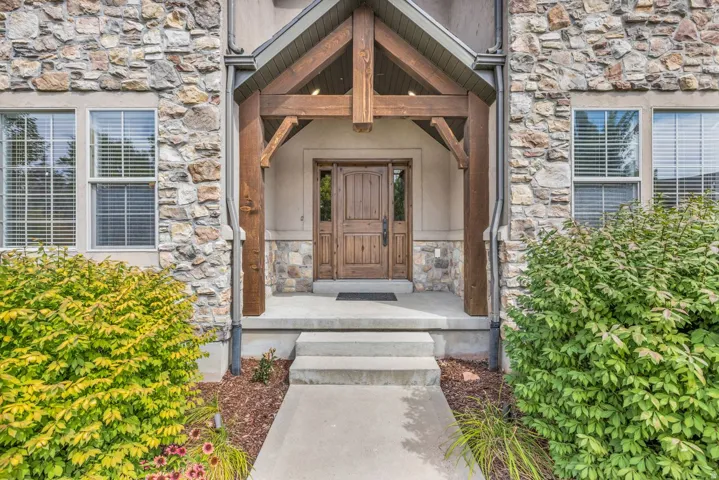 Stone facade with an exposed beam entryway and a solid wood front door