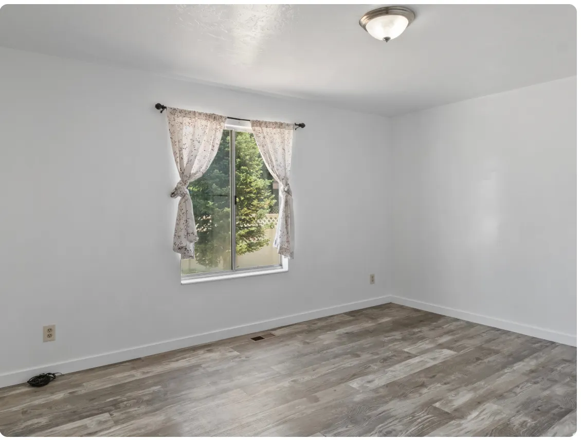 Window with outdoor scenery, overhead flush mount light fixture, wood-finish flooring, and white walls