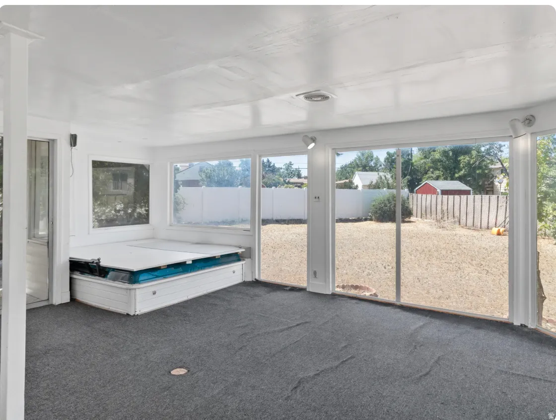 Enclosed patio featuring expansive windows, track lighting, and a built-in hot tub