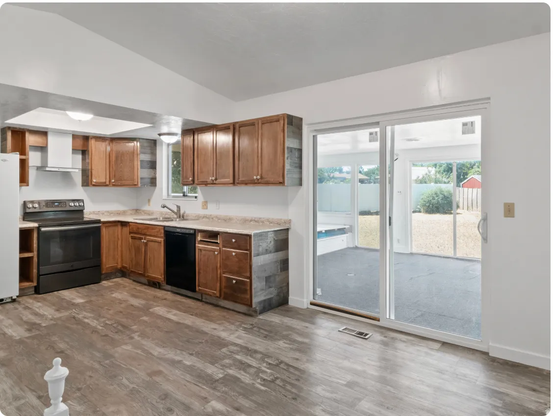 Vaulted ceiling kitchen featuring wood-finish flooring, wood cabinetry, and a range with a white vent hood